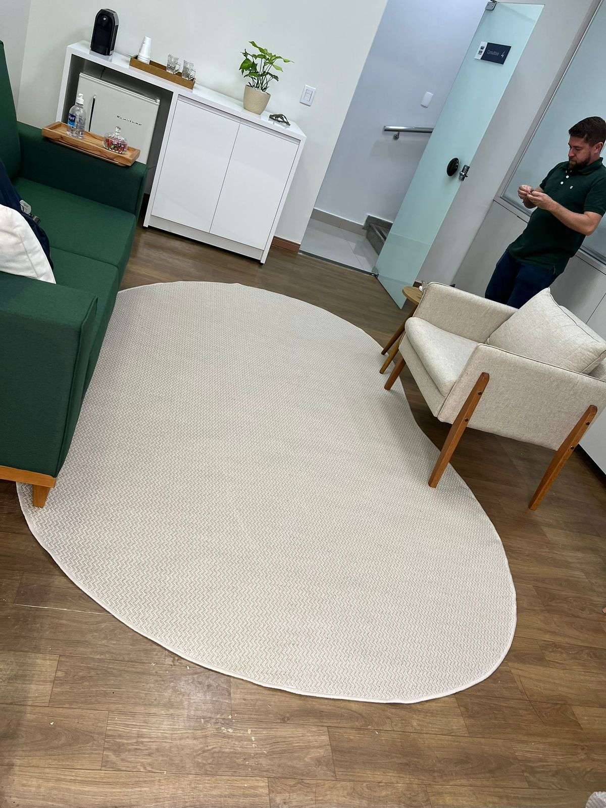 Tapete orgânico oval em tom cru instalado em sala de espera